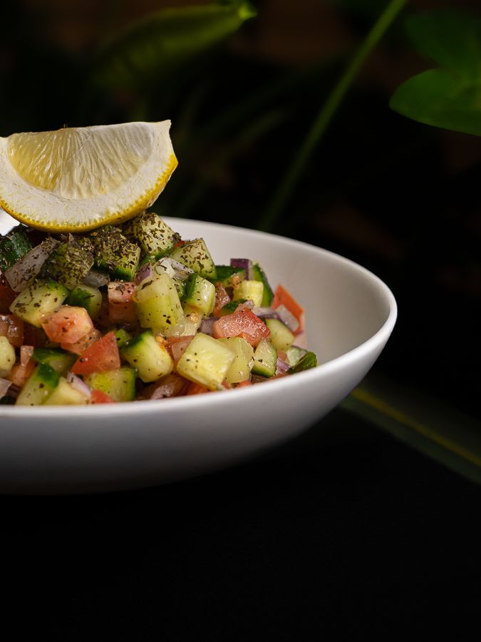 A bowl of Shirazi salad with a lemon wedge