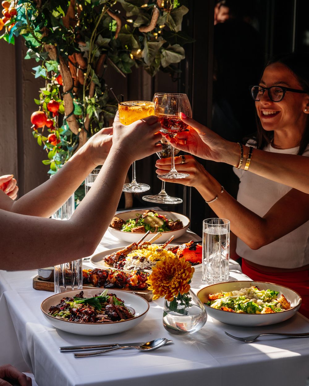 Friends raising glasses over shared plates at Shiraz Kitchen, Chelsea