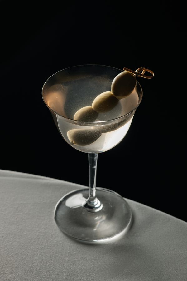 A martini with three olives on a pick