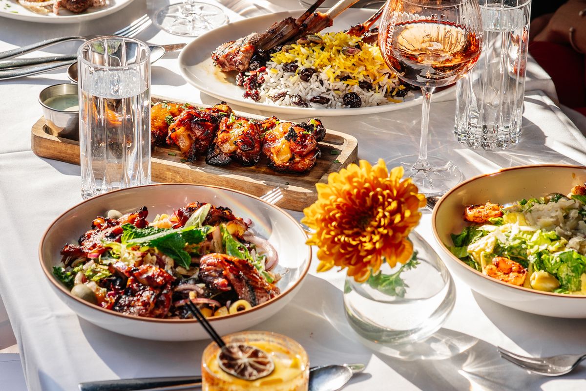 A table of shared plates, drinks and orange flowers in Chelsea